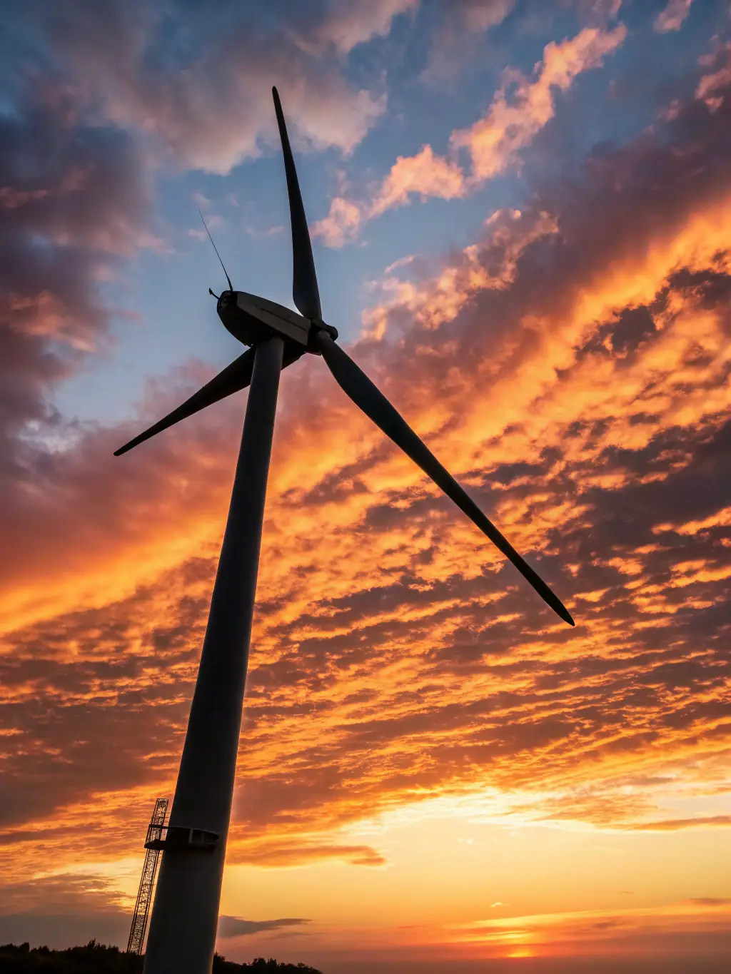 A high-tech wind turbine with advanced sensors and aerodynamic blades, set against a backdrop of a coastal wind farm at sunset.